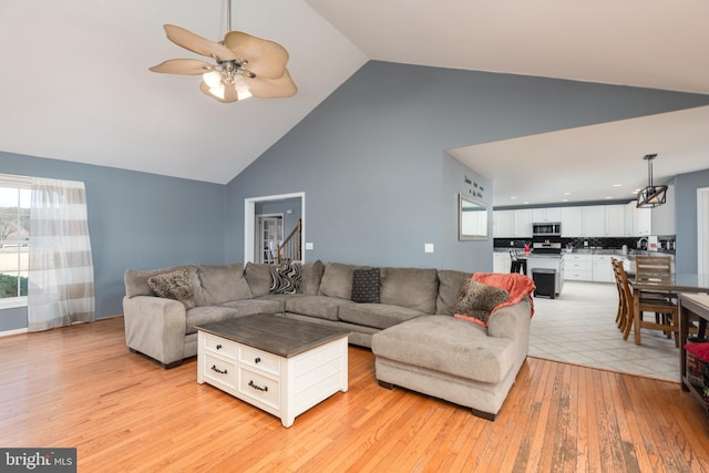 living room with high vaulted ceiling, light wood-style flooring, and a ceiling fan