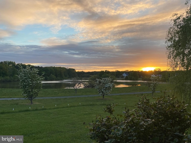 yard at dusk featuring a water view