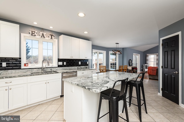 kitchen featuring light stone counters, light tile patterned flooring, a sink, white cabinets, and backsplash