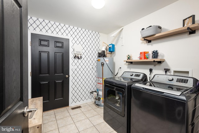 laundry area featuring light tile patterned floors, gas water heater, laundry area, visible vents, and washer and clothes dryer