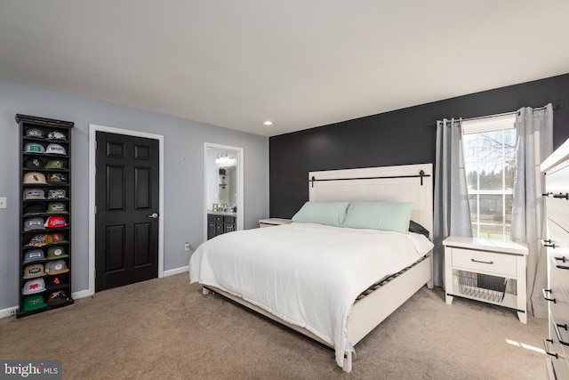 carpeted bedroom with ensuite bath and baseboards