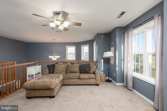 carpeted living area featuring visible vents, baseboards, and ceiling fan with notable chandelier