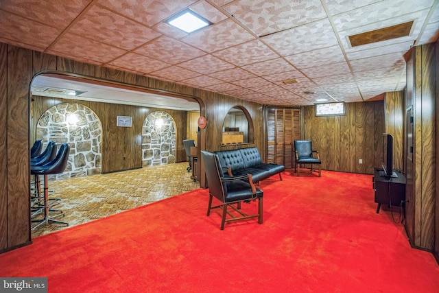 living area with carpet and wooden walls