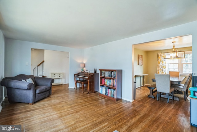 living area featuring baseboards, stairway, an inviting chandelier, and wood finished floors