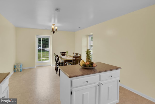 kitchen featuring a healthy amount of sunlight, a kitchen island, baseboards, and white cabinets