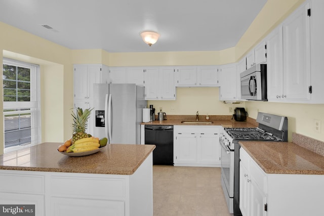 kitchen with white cabinetry, appliances with stainless steel finishes, a sink, and a center island