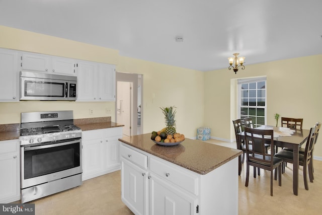 kitchen with a notable chandelier, stainless steel appliances, a center island, and white cabinets