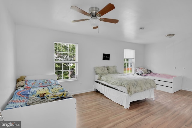 bedroom featuring light wood-type flooring, multiple windows, and baseboards