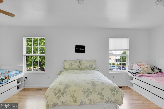 bedroom featuring light wood-style flooring, visible vents, baseboards, and ceiling fan