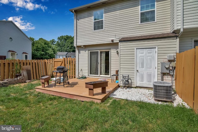 rear view of property with a wooden deck, fence, and a yard