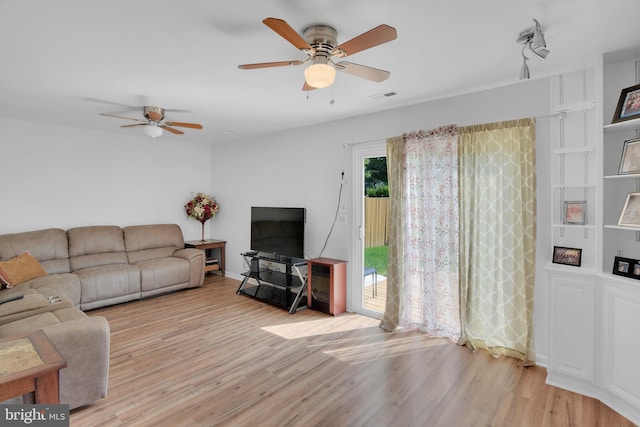 living room featuring light wood finished floors, visible vents, and a ceiling fan