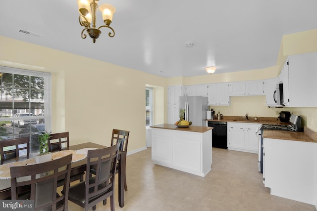 kitchen with stainless steel appliances, a kitchen island, a sink, white cabinetry, and dark countertops