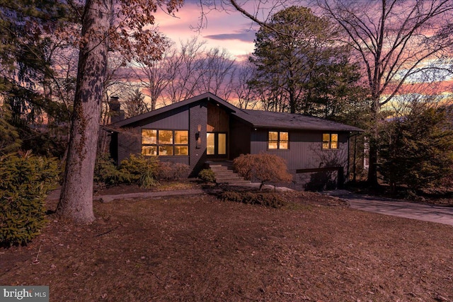 mid-century home with driveway and a chimney