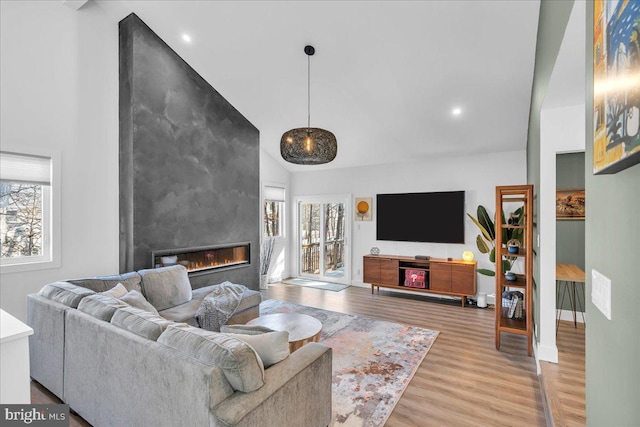 living area with light wood-style floors, recessed lighting, a fireplace, and high vaulted ceiling