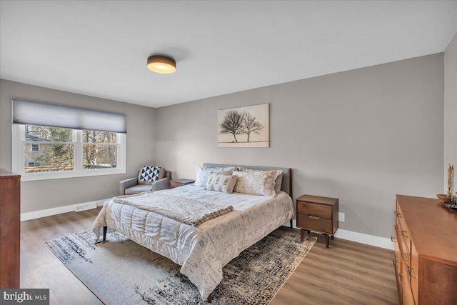 bedroom with visible vents, baseboards, and wood finished floors