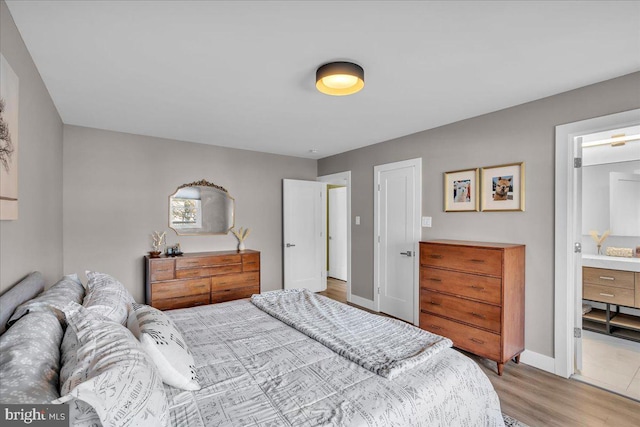 bedroom with light wood-style floors, baseboards, and ensuite bathroom