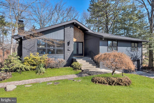 mid-century home featuring an attached garage, a chimney, aphalt driveway, and a front yard