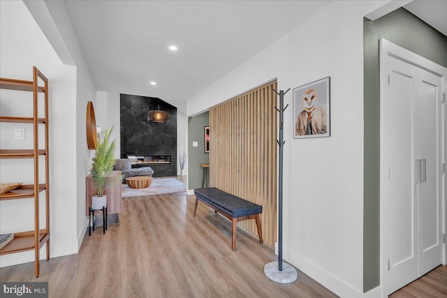 hallway with light wood-style floors, recessed lighting, arched walkways, and baseboards