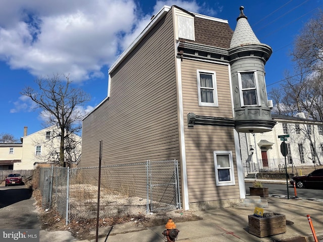 view of side of home with roof with shingles and fence