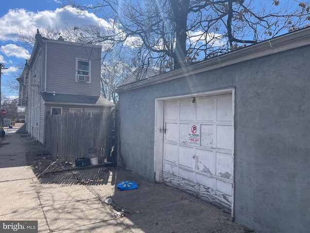 view of side of property with a garage, fence, and stucco siding