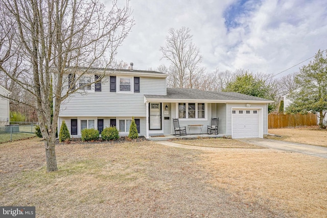 split level home featuring a garage, fence, and concrete driveway