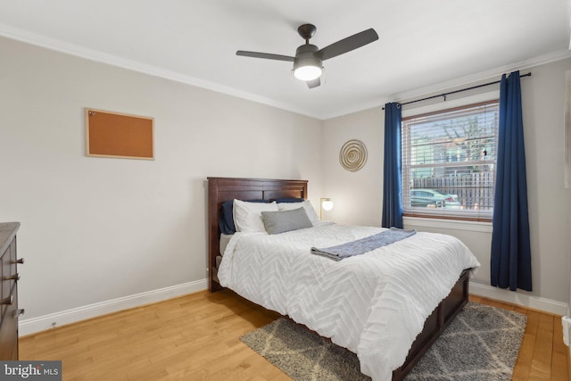 bedroom with a ceiling fan, baseboards, wood finished floors, and ornamental molding