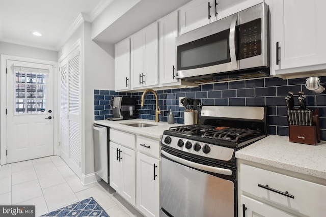 kitchen featuring light tile patterned floors, light stone counters, stainless steel appliances, a sink, and white cabinetry