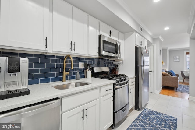 kitchen with visible vents, appliances with stainless steel finishes, ornamental molding, white cabinetry, and a sink