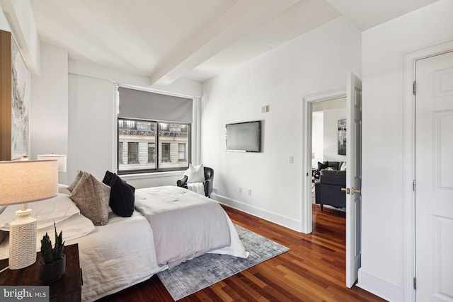 bedroom with beamed ceiling, baseboards, and wood finished floors