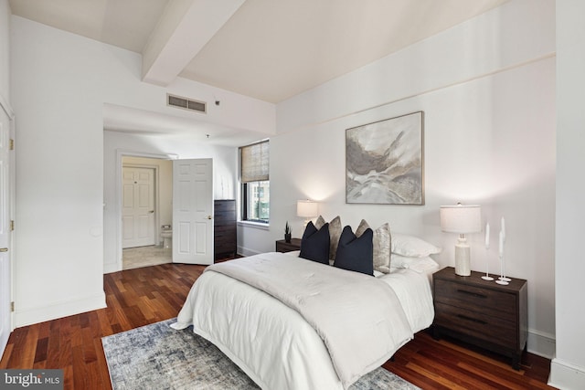 bedroom with beamed ceiling, baseboards, visible vents, and wood finished floors