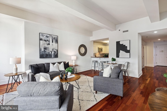 living room with beam ceiling, visible vents, baseboards, and wood finished floors