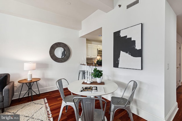 dining space with wood finished floors, visible vents, and baseboards