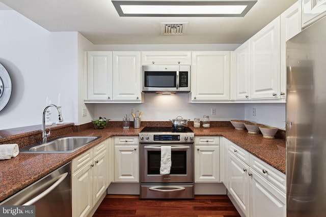 kitchen with visible vents, dark wood-type flooring, a sink, white cabinetry, and stainless steel appliances