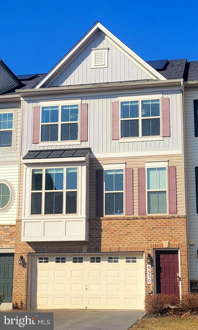 view of home's exterior with a garage, a standing seam roof, roof mounted solar panels, and board and batten siding