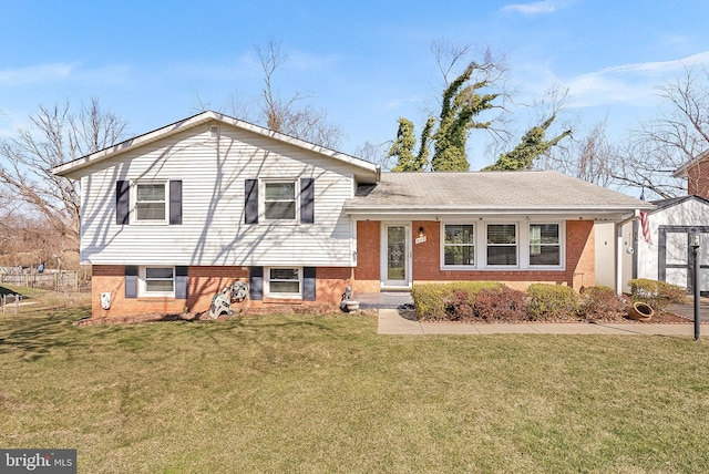 tri-level home featuring brick siding, an outdoor structure, and a front lawn