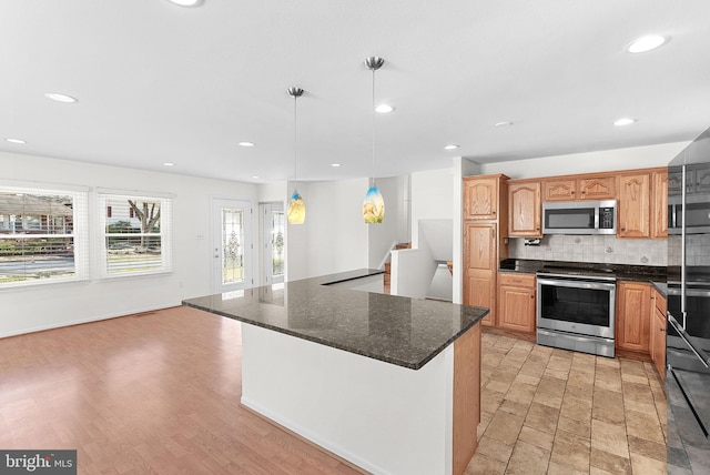 kitchen featuring recessed lighting, stainless steel appliances, a kitchen island, tasteful backsplash, and decorative light fixtures