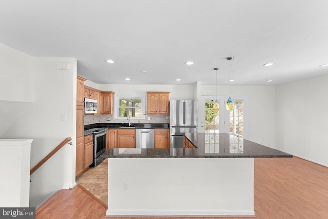 kitchen with recessed lighting, a kitchen island, appliances with stainless steel finishes, light wood-type flooring, and decorative backsplash