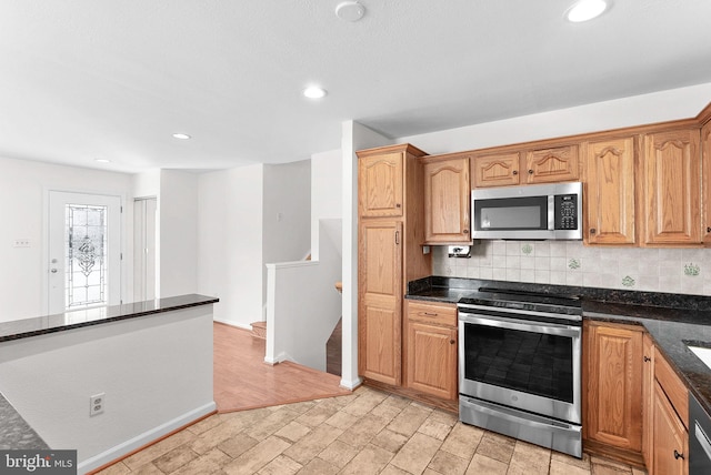 kitchen featuring dark stone counters, appliances with stainless steel finishes, decorative backsplash, and recessed lighting