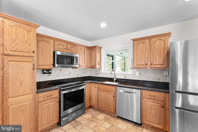 kitchen with stainless steel appliances, recessed lighting, decorative backsplash, stone finish flooring, and a sink