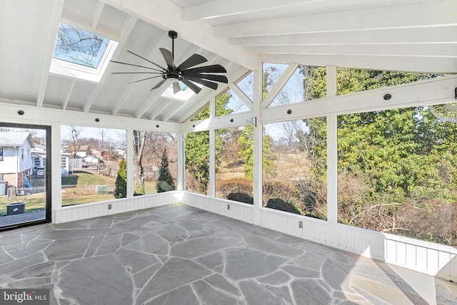 unfurnished sunroom with a wealth of natural light, vaulted ceiling with skylight, and ceiling fan