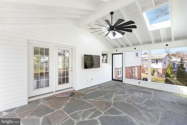 sunroom / solarium featuring lofted ceiling with skylight, a ceiling fan, and a healthy amount of sunlight