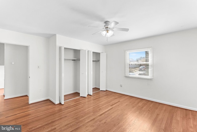 unfurnished bedroom with light wood-style flooring, baseboards, ceiling fan, and multiple closets