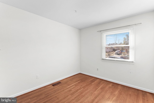 empty room with light wood-type flooring, visible vents, and baseboards