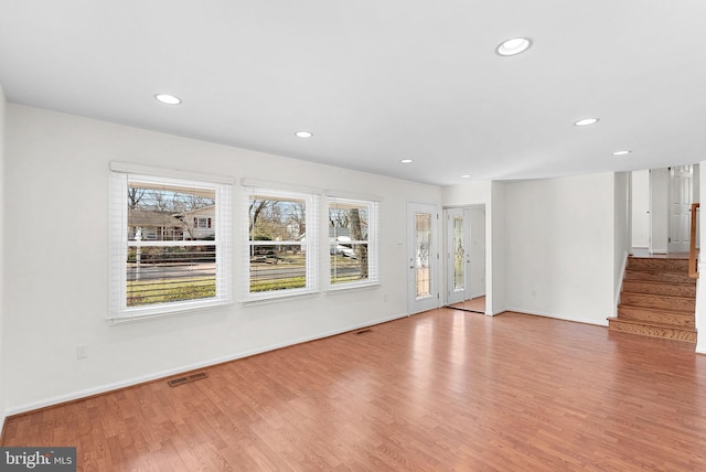 unfurnished living room with stairs, recessed lighting, visible vents, and wood finished floors