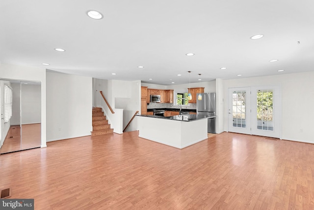 kitchen with dark countertops, light wood-style floors, stainless steel appliances, and open floor plan