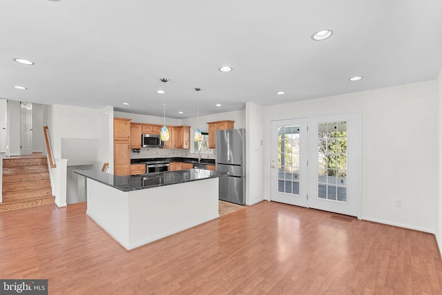 kitchen featuring dark countertops, light wood-type flooring, tasteful backsplash, and stainless steel appliances