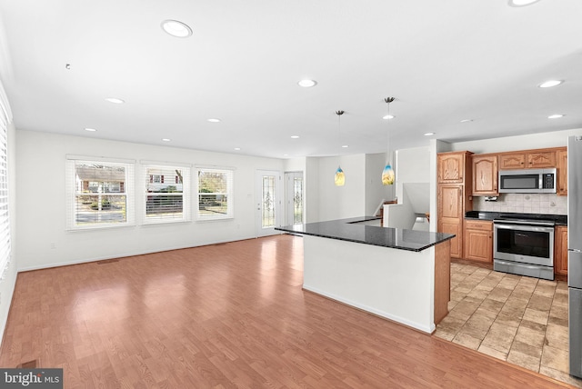 kitchen with stainless steel appliances, dark countertops, recessed lighting, decorative backsplash, and light wood-style floors