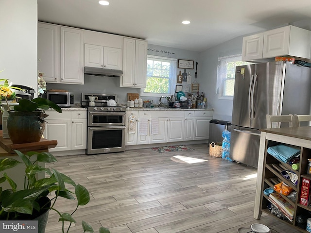 kitchen featuring appliances with stainless steel finishes, light wood-style flooring, white cabinets, and under cabinet range hood