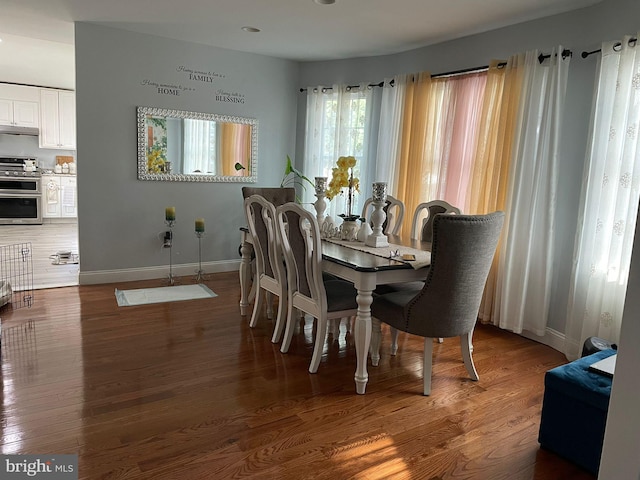 dining space with baseboards and wood finished floors