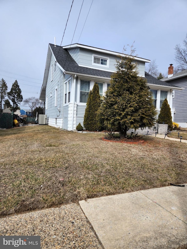 view of front of home with central air condition unit and a front yard